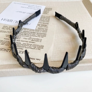 Detail of punk style headband with black cone spikes and shimmering dark grey fabric
