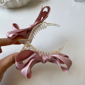 Dettaglio molletta per capelli con fiocco in seta rosa in raso e denti trasparenti