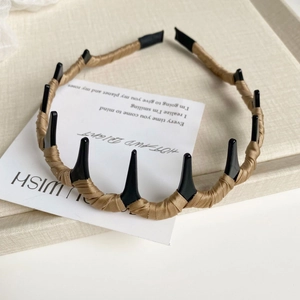 Détail d'un serre-tête ondulé style punk avec pointes noires sur carte décorative