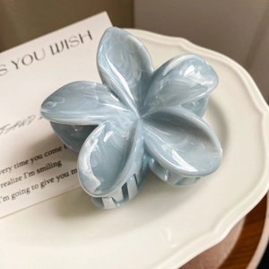Detail of blue and white marble pattern acetate flower hair claw clip on ceramic plate