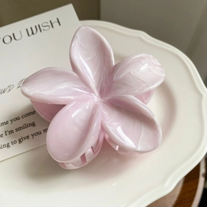 Macro shot of pink marble texture plumeria hair claw clip on white porcelain plate