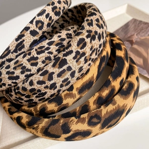 Detailed macro view of retro leopard print headbands on a textured minimalist tray
