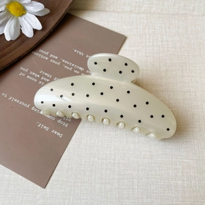 Detailed view of beige polka dot claw clip with elegant small pearls along the base edge