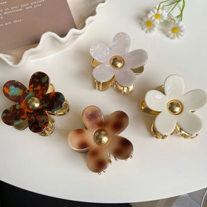 Détail de quatre pinces à cheveux fleurs en acétate avec textures marbrées et dorées