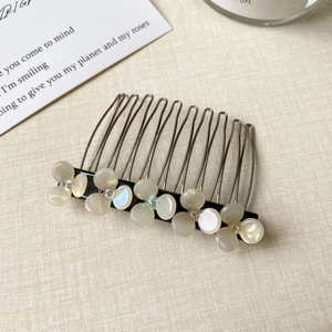 Detail of metal hair comb with five pearlescent flowers and inlaid sparkling crystals