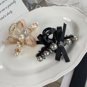 Détail de pinces à cheveux élégantes avec perles et nœuds en soie sur plateau