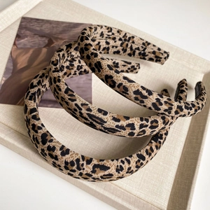 Detailed close-up of wide leopard print fabric headbands in a stylish retro layout