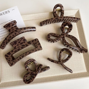 Set of 6 leopard print hair claws in various geometric shapes on a linen tray