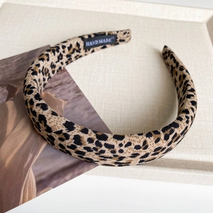 Detailed macro view of leopard print fabric headband featuring a handmade inner woven label