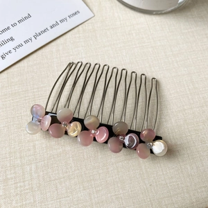 Close-up of pink iridescent flower hair comb with rhinestones and metal teeth
