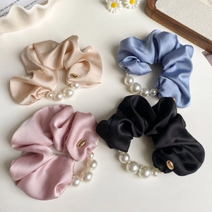 Elegant four-piece silk scrunchie set with large pearls in champagne, blue, pink, and black