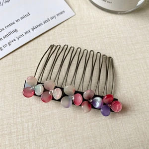 Close-up of metal hair comb with gradient resin flowers and sparkling rhinestones