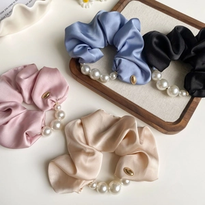 Detail view of satin pearl hair scrunchies set in pink, blue, black, and champagne colors