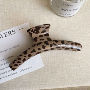 Detail of large leopard print hair claw clip with glossy resin finish on beige fabric
