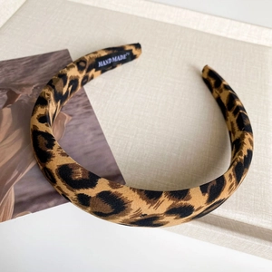 Detail view of leopard print fabric headband featuring a woven Hand Made inner label