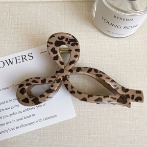 Detail of a large leopard print hair claw clip with a stylish bow-knot design on a table