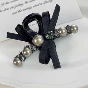 Détail macro d'une pince à cheveux à nœud noir avec perles grises et diamants en verre