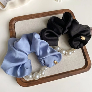 Detailed close-up of lavender and black silk satin scrunchies with gradient pearls