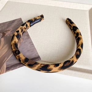 Close-up of leopard print fabric headband with a black handmade label on the inner side
