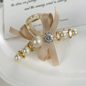 Détail de la pince à cheveux noeud en satin champagne avec perles et diamants marquise