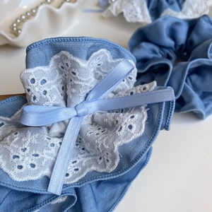 Detailed close-up of light blue tencel hair scrunchie with white lace and ribbon bow