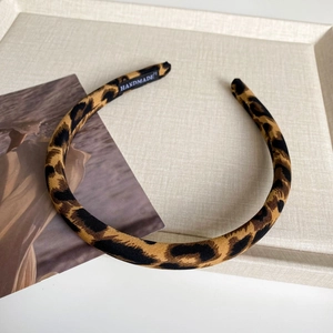 Close-up of leopard print headband fabric with a black Handmade woven label inside