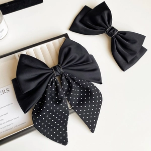 Close-up of black satin bow hair clips with polka dot ribbons and rhinestone center detail