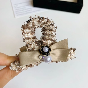 Detail of tweed hair claw with satin bow, camellia flower, white pearls and sparkling rhinestone
