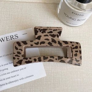Detail of large leopard print hair claw clip with glossy resin finish on soft fabric