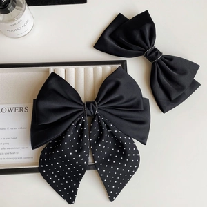 Close-up of elegant black satin bow hair clips with polka dots and crystal accents