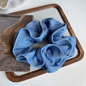 Detailed view of light blue tencel denim fabric scrunchie with fine woven texture