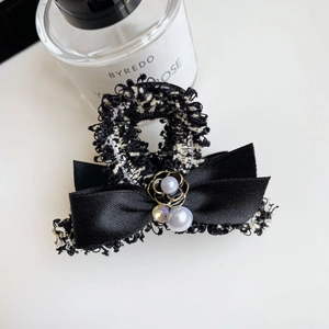 Detail view of tweed bow hair claw clip with pearls and golden floral embellishments