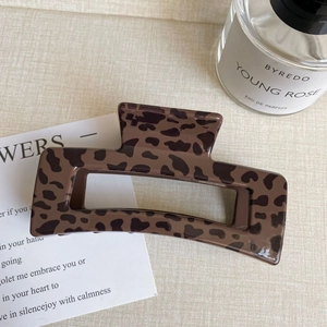 Close-up of a large leopard print hair claw clip on fabric with decorative accessories
