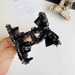 Detail of tweed bow hair claw clip featuring black and white woven texture and a durable grip