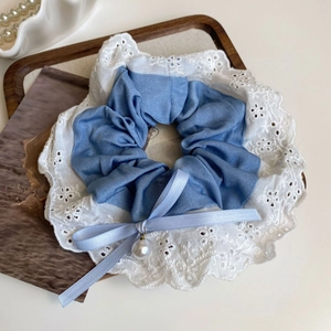 Detail of blue denim scrunchie with lace edge, ribbon bow, and pearl pendant