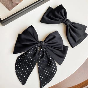 Close-up of black satin bow hair clips with polka dot ribbons and rhinestone details