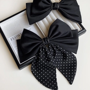Detail of elegant black satin bow hair clips with sparkling rhinestone center and polka dots