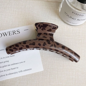 Macro detail of curved leopard print hair claw clip with glossy resin finish