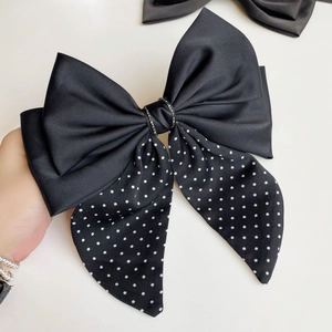 Detail of black satin bow hair clip with silver rhinestone center and white polka dots