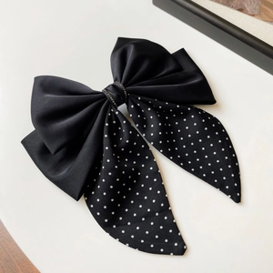 Macro detail of large black satin bow hair clip with white dots and crystal center
