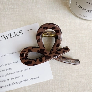 Detail of leopard print hair claw clip with gold metal spring on textured background
