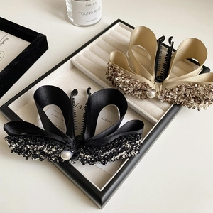 Elegant bow hair clips set in black and champagne gold with tweed edges and pearl detail