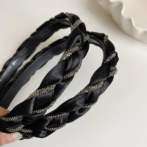 Detailed close-up of a black braided headband with shimmering silver rhinestones