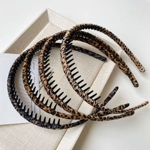 Detail view of four leopard print headbands with non-slip teeth on a cream tray