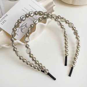 Détail de serre-têtes à perles métalliques argentées sur un plateau blanc chic
