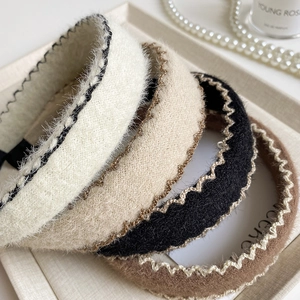 Gros plan de serre-têtes tressés larges blanc beige et noir avec texture pelucheuse