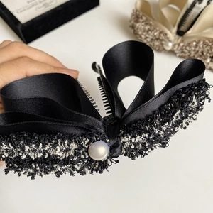 Detail view of tweed and satin bow banana clip with a pearl accent for elegant styling