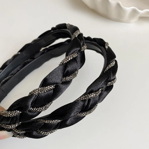 Detailed view of the black braided satin headband with sparkling rhinestone chain