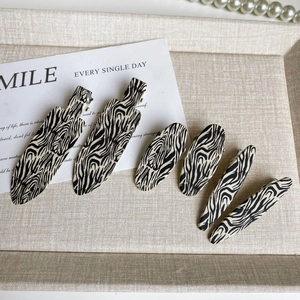 Close-up of 6-piece zebra pattern hair clip set including metal barrettes on beige tray