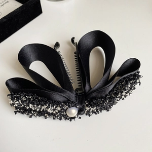Detail of banana hair clip with black satin ribbon, tweed fabric and faux pearl accent